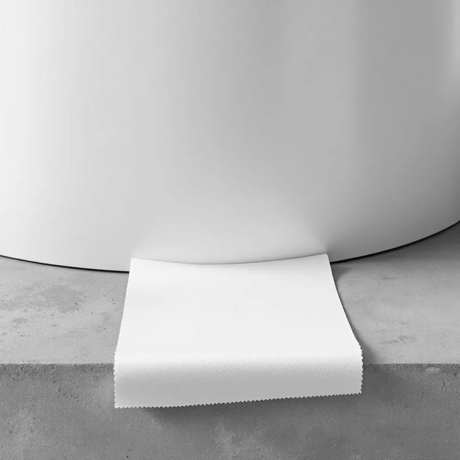 Single sheet of white paper towel laid flat on concrete against the blank curved base of a white water heater tank
